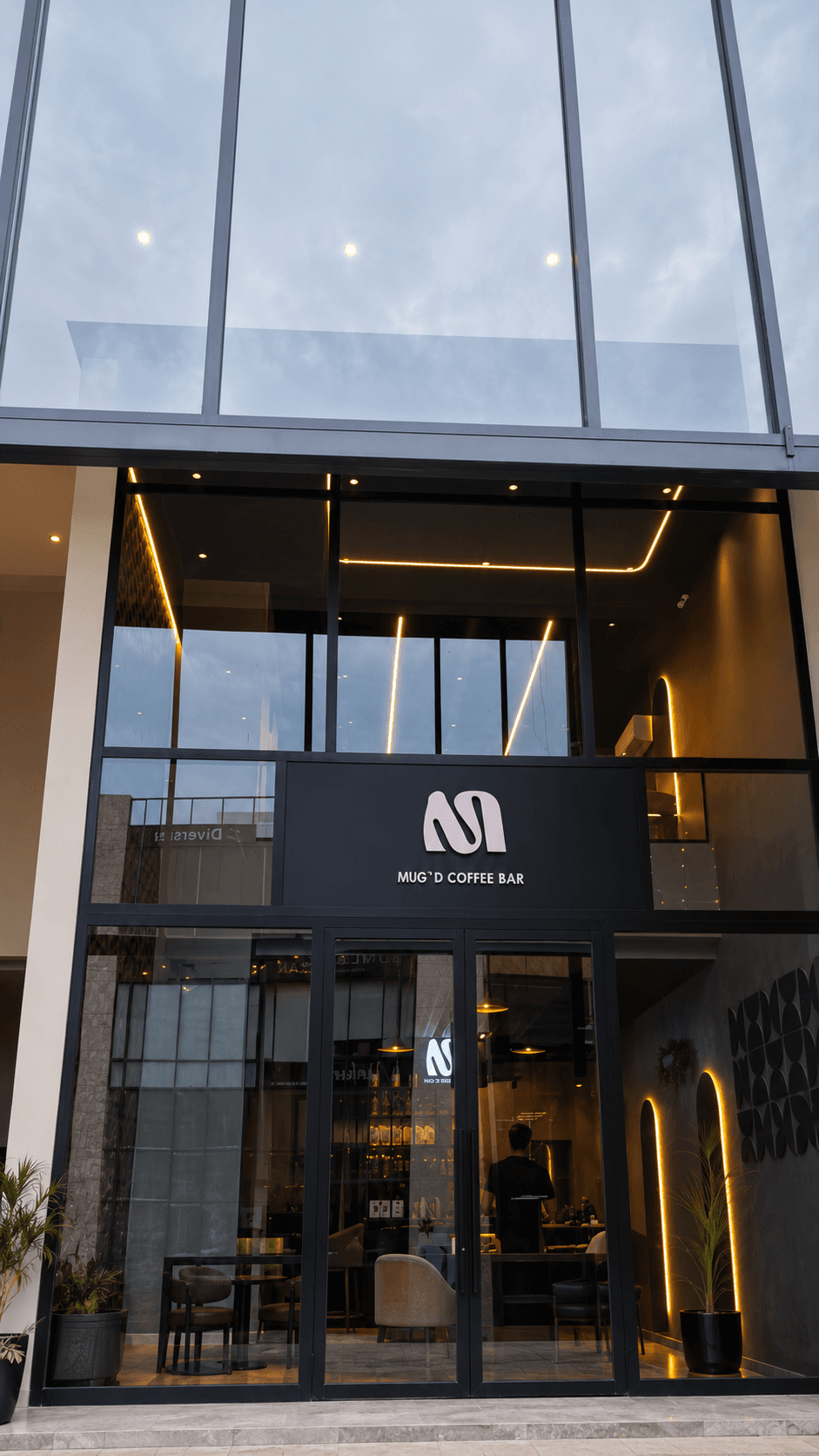 MUG'D Coffee Bar exterior facade with warm lighting and signage